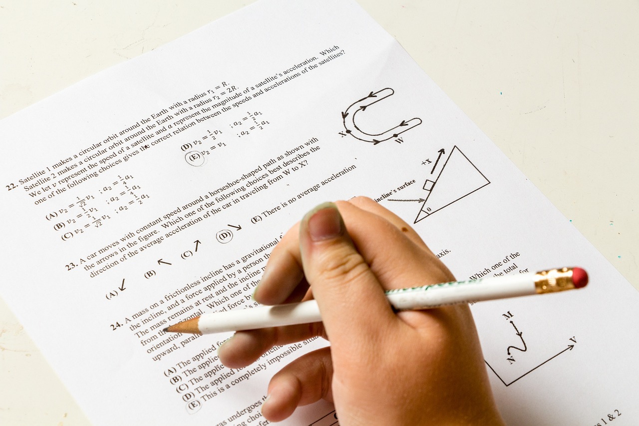 Hand holding pencil doing a maths exam